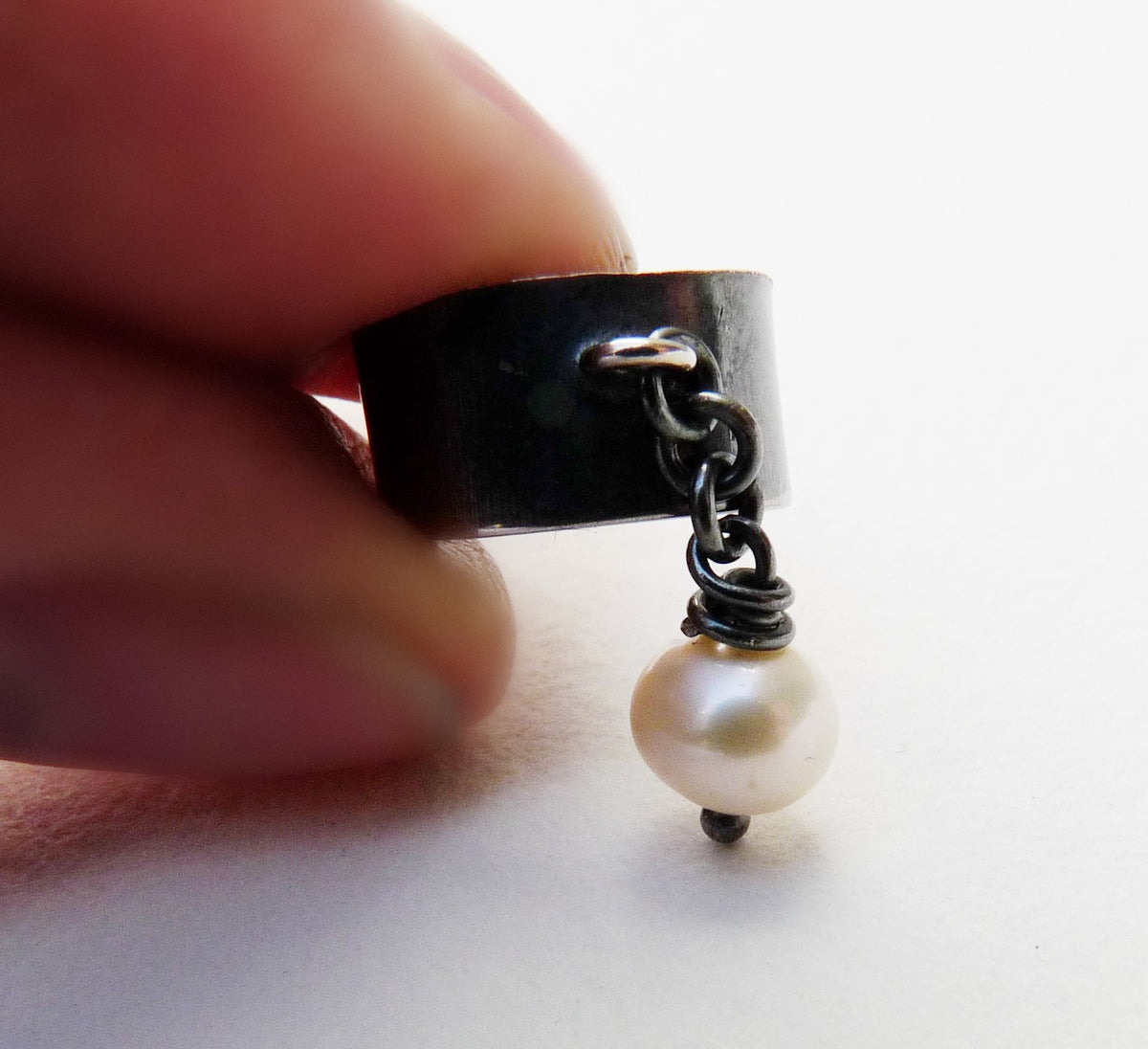 Minimalistische zilveren heren oorklem met zoetwaterparel in de hand