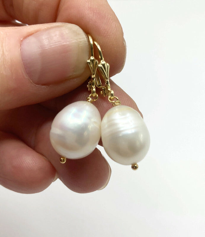 Close-up van de grote witte zoetwaterparels in een hand om de grootte te tonen