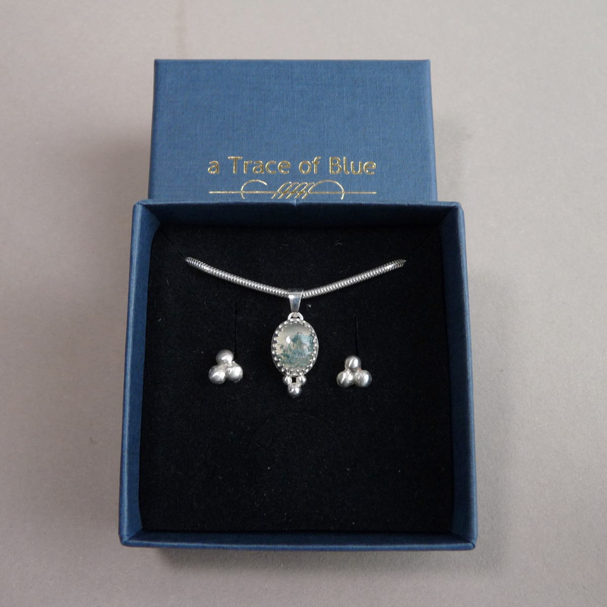 Een handgemaakte zilveren ketting met hanger gepresenteerd in een luxe blauw aTraceof Blue sieraaddoosje
