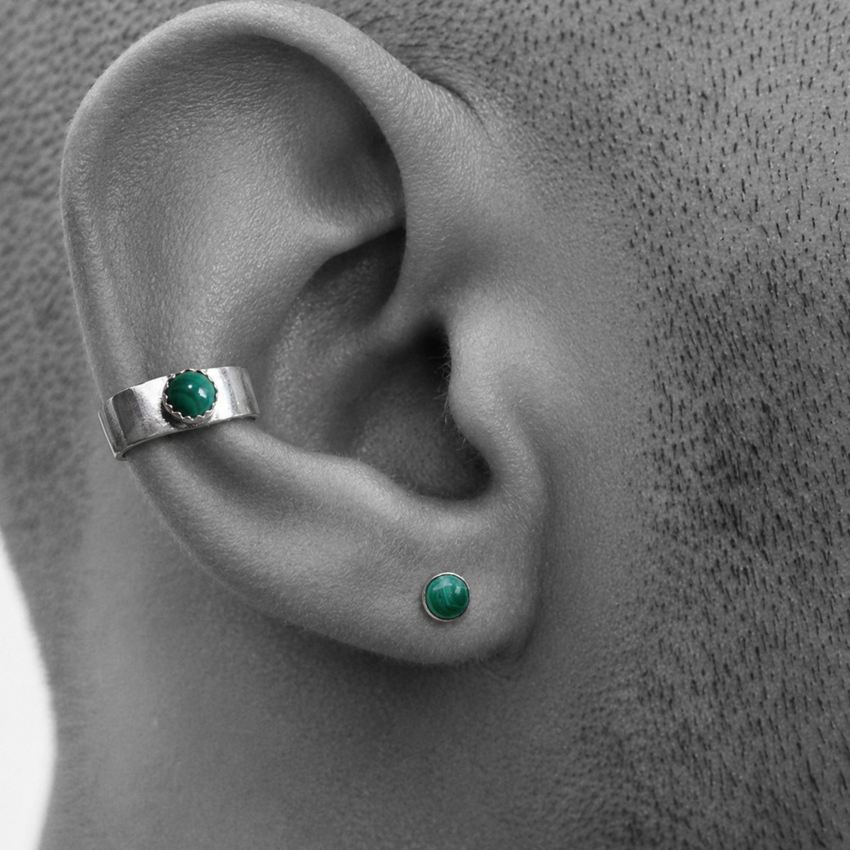 Mannelijk model draagt een zilveren heren ear cuff gecombineerd met een groen malachiet oorknopje