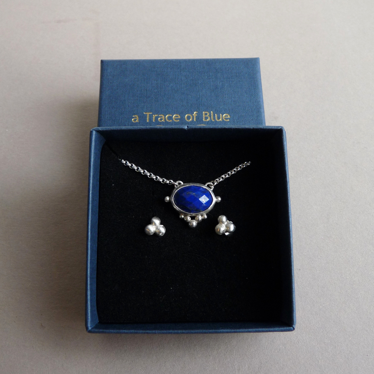 Bijpassende zilveren sieradenset van een ketting en hangende oorbellen met facetgeslepen lapis lazuli edelstenen