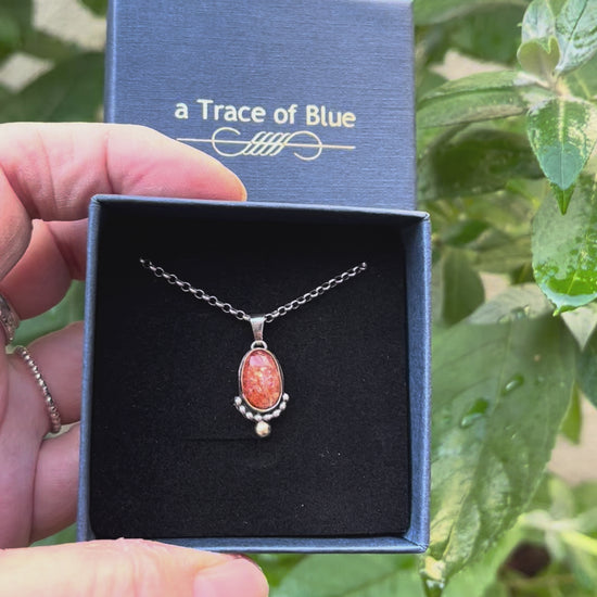 Handgemaakte tweekleurige edelsteen ketting met zonnesteen vastgehouden in de hand