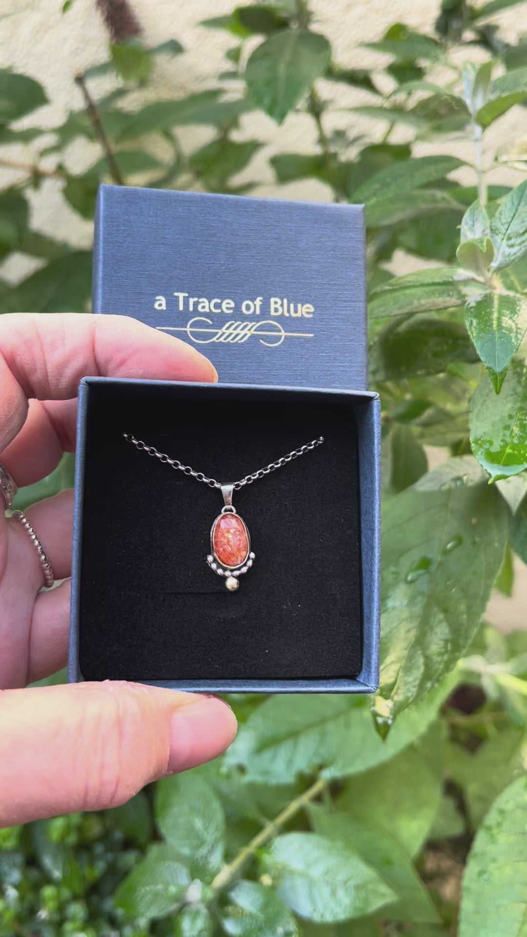 Handgemaakte tweekleurige edelsteen ketting met zonnesteen vastgehouden in de hand
