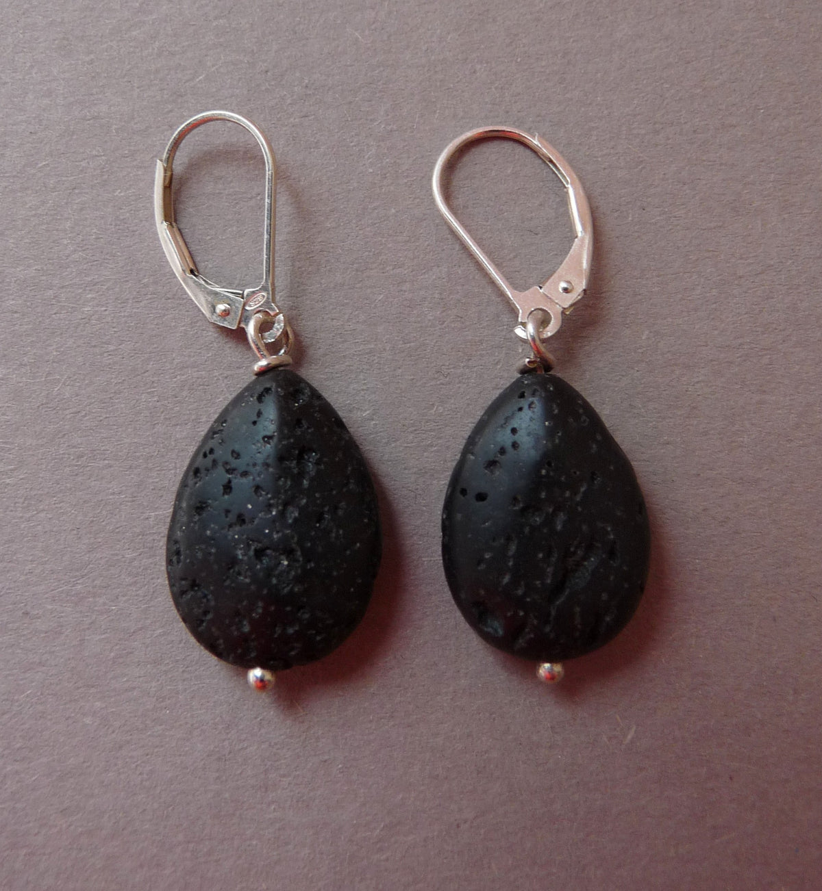 Single men's silver earring with lava stone droplet, perfect for a unique ear stack