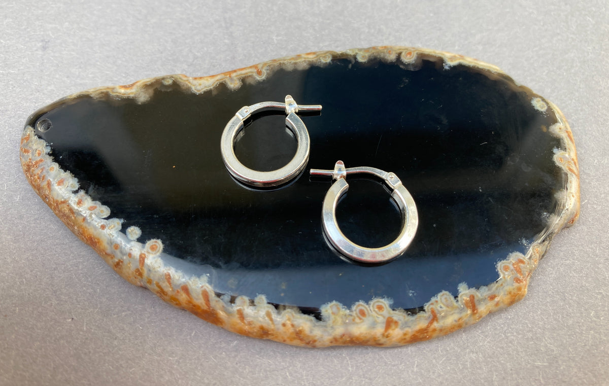 Twee 925 sterling zilveren heren oorbellen met scharniersluiting gepresenteerd op een display