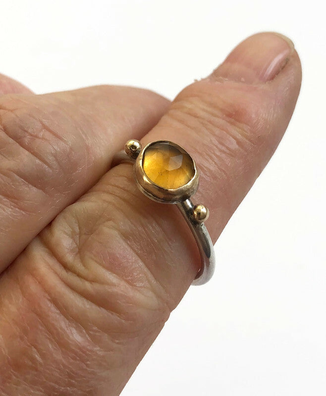 Handgemaakte zilveren en gouden stapelringen met een citrien edelsteen gedragen om de vinger