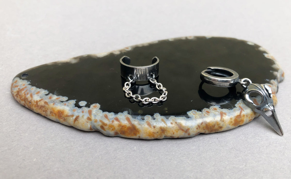 Limited edition zilveren heren ear cuff met raven skull op een displaysteen
