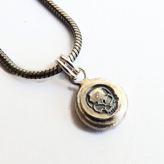 Detailopname van de handgemaakte zilveren skull hanger op een geoxideerde slangenketting