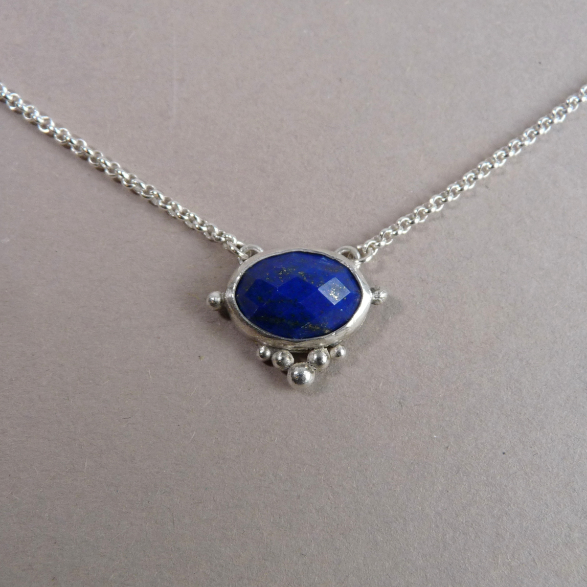 Handgemaakte zilveren ketting met een facetgeslepen blauwe lapis lazuli edelsteen hanger en zilveren granules