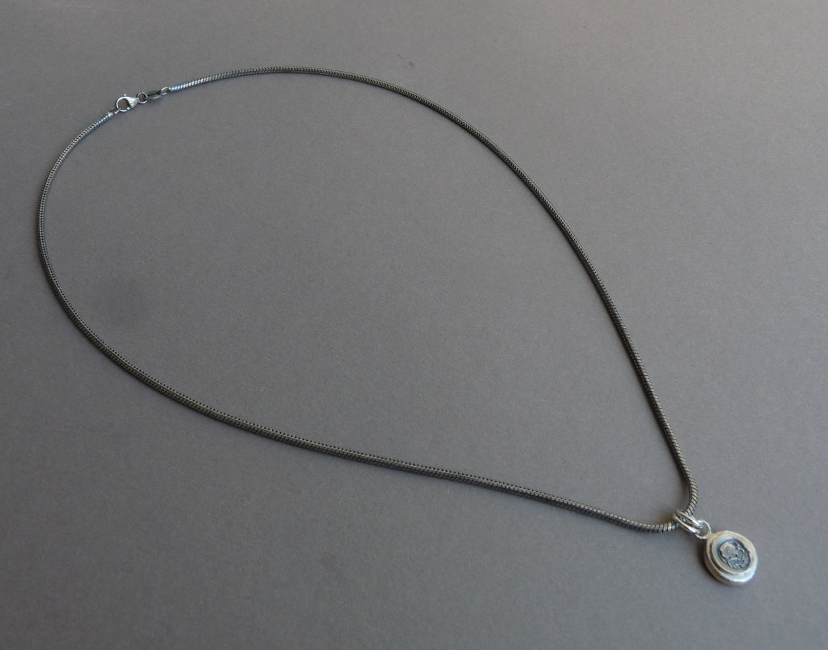 Minimalistische zilveren herenketting met skull hanger plat gefotografeerd